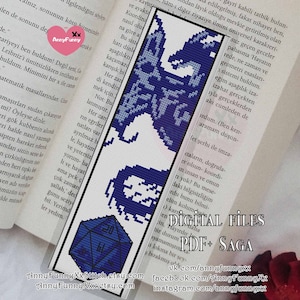 Könnte beinhalten: Blau-weißer Lesezeichen mit einem pixeligen Drachendesign und einem Würfel. Das Lesezeichen liegt auf einem Buch. Der Text "DIGITAL FILES PDF+ SAGA" ist ebenfalls sichtbar.
