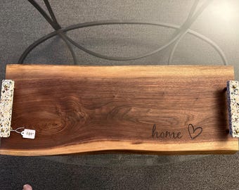 May include: A rectangular wooden serving tray with a live edge and a dark brown finish. The tray has handles with a speckled, light-colored design and the word "home" with a heart is engraved on the surface.