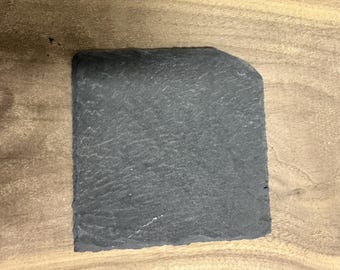 May include: A black slate serving tray with a rough, textured surface. The tray is rectangular and has slightly rounded edges.