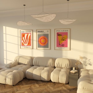 K&ouml;nnte beinhalten: Ein wei&szlig;es modulares Sofa mit drei Teilen und einem kleinen Beistelltisch. An der Wand hinter dem Sofa h&auml;ngen drei gerahmte Poster mit abstrakter Kunst. Die Poster sind mit "Henri Matisse", "Bauhaus" und "Picasso" betitelt.