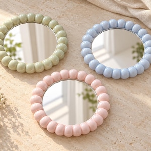 May include: Three circular mirrors with thick, rounded, bubble-like frames in pastel sage green, light blue, and soft pink. Each mirror features a smooth, reflective glass center surrounded by a continuous ring of uniform, glossy spheres.