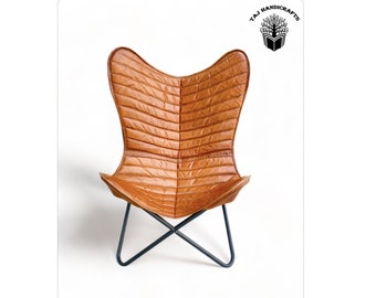 May include: A brown leather butterfly chair with a quilted design and a black metal frame.