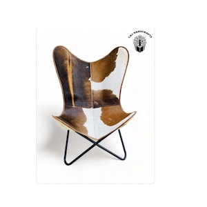 May include: A brown and white cowhide butterfly chair with a black metal frame. The chair is on a white background.