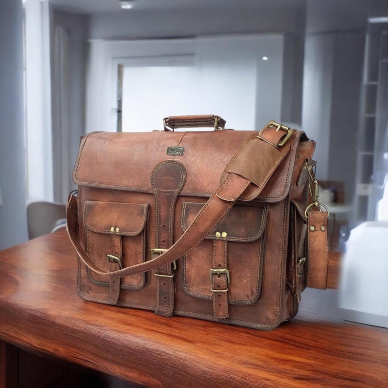 May include: A brown leather messenger bag with multiple pockets and buckles. The bag has a long adjustable strap and a small leather handle.