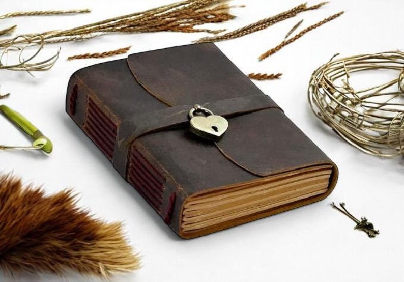 May include: A brown leather journal with a heart-shaped lock and a strap closure. The journal has a rustic look and is perfect for writing down your thoughts and ideas.