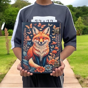 May include: A leather-bound journal with a colorful illustration of a fox surrounded by flowers and butterflies. The journal has two metal clasps and a decorative design.