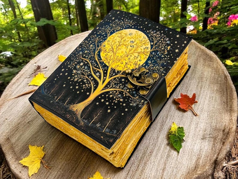 May include: A black leather-bound journal with a gold-leaf design of a tree and a full moon. The journal has a brass clasp and is closed.