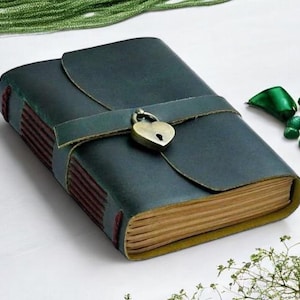 May include: A dark green leather journal with a heart-shaped lock and a brown leather strap. The journal has a rustic look and is perfect for writing down your thoughts and ideas.