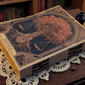 May include: A decorative book with a detailed illustration of a tree with scales on the cover. The word "JUSTICE" is printed on the side. The book is on a wooden surface with a candle, inkwell, and skull nearby.