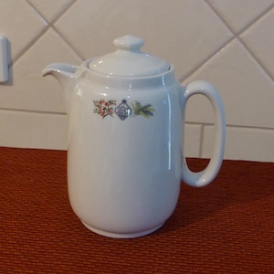 May include: White ceramic coffee pot with a floral design and a lid. The pot has a handle and a spout.