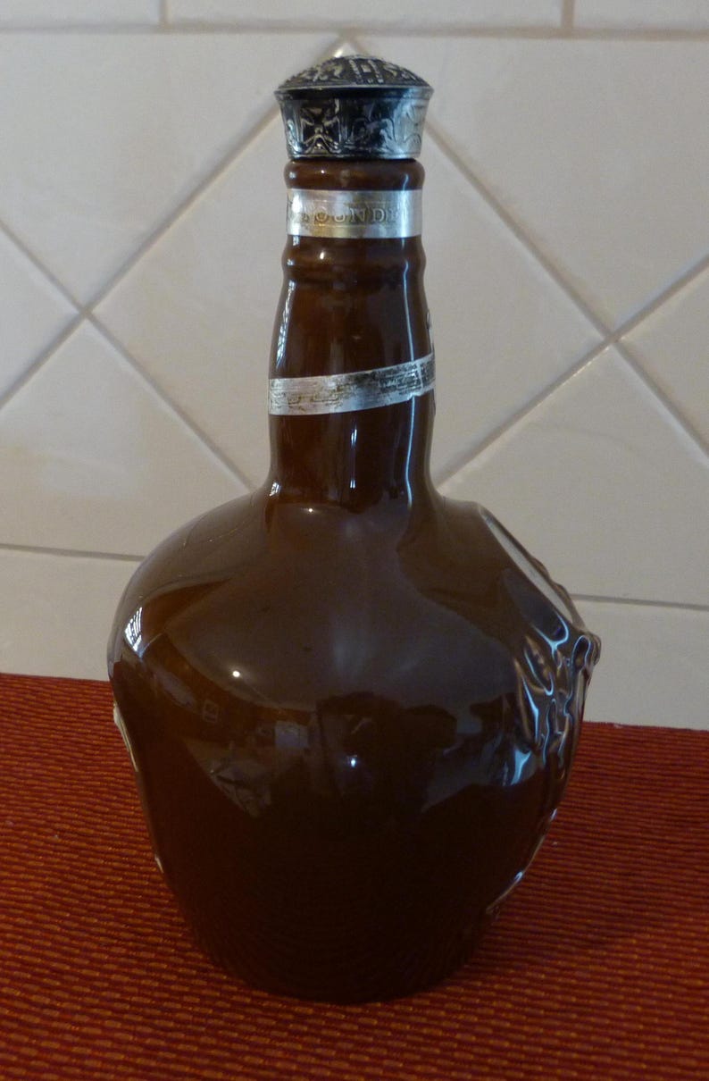 May include: A brown ceramic bottle with a silver cap. The bottle has a unique shape and a silver label with the text "Johnnie Walker" on it.