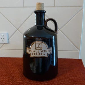 May include: A dark brown ceramic wine bottle with a cork stopper and a label that reads "Tisdall Wines Echuca".