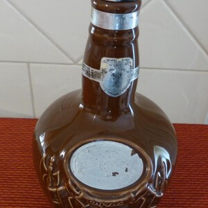 May include: A brown ceramic bottle with a silver top and a silver label that says "Chivas Regal" and "12 Years Old".