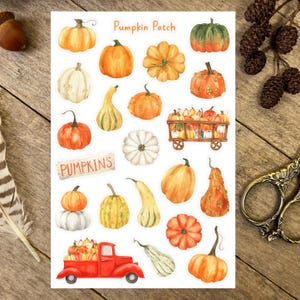 May include: A sheet of watercolour stickers featuring pumpkins in orange, green, and white. The stickers depict various pumpkin shapes and sizes, a red truck, and the text "Pumpkin Patch" and "Pumpkins".