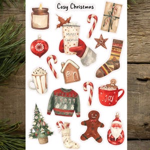 May include: A set of 14 Christmas-themed stickers featuring illustrations of a gingerbread house, a Christmas tree, a gingerbread man, a stocking, a candy cane, a mug of hot chocolate, a sweater, a candle, a star, a Christmas bauble, and a mug with the word "Joy" on it. The stickers are on a white background and have a watercolour look.
