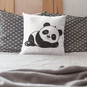 Pu&ograve; includere: Un cuscino bianco con un'illustrazione di un orso panda bianco e nero. Il panda &egrave; sdraiato con gli occhi chiusi. Il cuscino &egrave; su un letto con una coperta grigia.