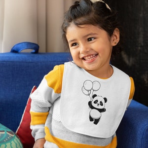 Pu&ograve; includere: Un bavaglino bianco con un orso panda bianco e nero che tiene dei palloncini. Il panda indossa un papillon rosso. Il bavaglino &egrave; indossato da un bambino piccolo con una camicia a righe gialle e bianche.