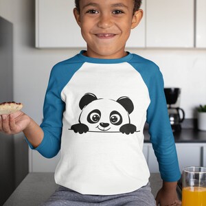 Pu&ograve; includere: Una maglietta bianca a maniche lunghe con un design a maniche raglan blu. La maglietta presenta un panda di cartone animato bianco e nero che sporge dal bordo della maglietta.
