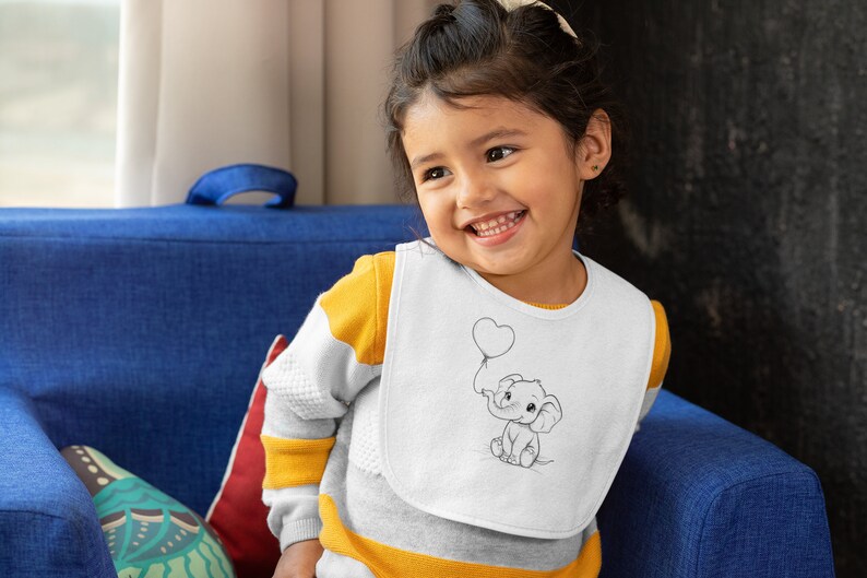 May include: A young child wearing a white bib with a black and white illustration of an elephant holding a heart-shaped balloon. The bib has a yellow and white striped shirt underneath.