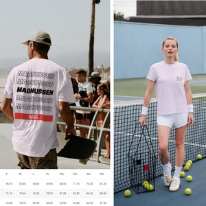 Puede incluir: Camisetas blancas con texto. Una tiene el nombre "MAGNUSSEN" apilado en la espalda con "HAAS" debajo. La otra es de color lila claro con el n&uacute;mero "20" en la parte delantera. Ambas son de manga corta. Medidas en cm.