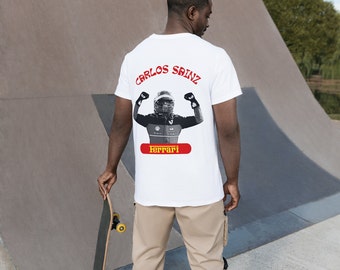 May include: White t-shirt with a graphic of Carlos Sainz in a racing suit, and the word "Ferrari" below. The text "Carlos Sainz" is arched above the graphic in red. The person is holding a skateboard.