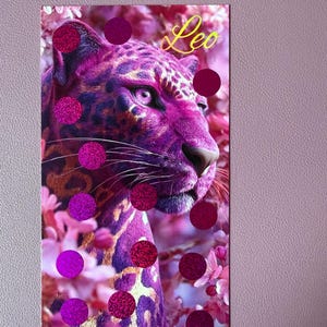 Könnte beinhalten: Ein rechteckiger Druck mit einem leuchtend violetten und magentafarbenen Leoparden, umgeben von rosa Blüten. Das Wort Leo steht in gelber Schreibschrift in der oberen rechten Ecke. Mehrere dunkelrosa glitzernde, kreisförmige Aufkleber sind platziert.