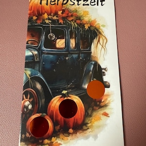 Könnte beinhalten: Eine Postkarte mit einem blauen Oldtimer, der mit Kürbissen und Herbstblättern geschmückt ist. Das Wort "Herbstzeit" ist oben aufgedruckt. Zwei Kürbisse befinden sich im Vordergrund, mit einem orangefarbenen runden Aufkleber auf der Karte.