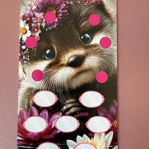 Könnte beinhalten: Eine Karte mit einem niedlichen Otter mit Blumenkrone und großen blauen Augen. Die Karte hat rosa Kreise und ovale Felder, mit dem Wort "Lose" auf einigen. Der Text "Miss Otti" steht oben. Der untere Teil der Karte zeigt Seerosen.