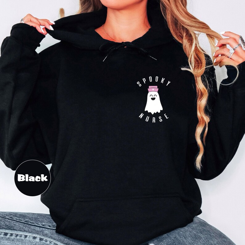 Pode incluir: Camisola de moletom com capuz preta com o texto "Spooky Nurse" e um fantasma de desenho animado usando um chap&eacute;u de enfermeira.