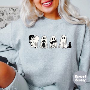 Pode incluir: Uma camisa de moletom cinza com um gr&aacute;fico de cinco fantasmas segurando gatos pretos. Os fantasmas s&atilde;o brancos e os gatos s&atilde;o pretos. O texto "Sport Grey" est&aacute; no canto inferior direito da imagem.