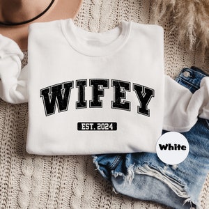 May include: White sweatshirt with black text that reads "WIFEY EST. 2024".