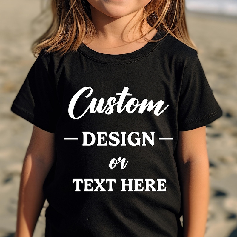 Puede incluir: Camiseta negra con texto blanco "Custom - DESIGN - or TEXT HERE". La camiseta de cuello redondo est&aacute; hecha de un material suave. El dise&ntilde;o es para ni&ntilde;os.