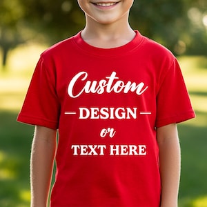 Puede incluir: Una camiseta roja con la palabra "Custom" en escritura blanca en el pecho. Debajo, el texto dice "- DESIGN - or TEXT HERE" en blanco, lo que sugiere un dise&ntilde;o personalizable. La camiseta es de manga corta.