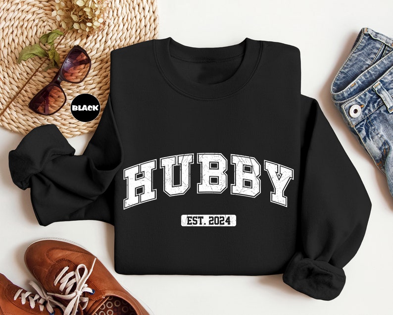 May include: Black sweatshirt with white text that reads "Hubby Est. 2024".