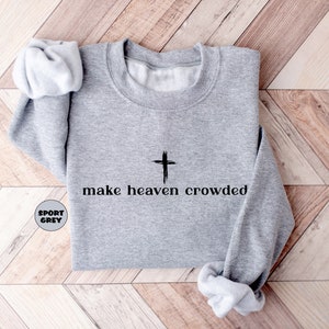 May include: A grey sweatshirt with a black cross and the text "make heaven crowded" printed on the front.
