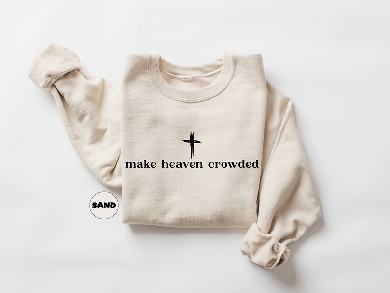 May include: A beige sweatshirt with a black cross and the text "make heaven crowded" printed on the front.