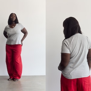 K&ouml;nnte beinhalten: Ein hellgraues kurz&auml;rmeliges T-Shirt mit V-Ausschnitt kombiniert mit einer locker sitzenden roten Hose. Das T-Shirt hat ein schlichtes, einfarbiges Design, w&auml;hrend die Hose weit geschnitten ist und bis zum Boden reicht, was ein l&auml;ssiges Outfit ergibt.