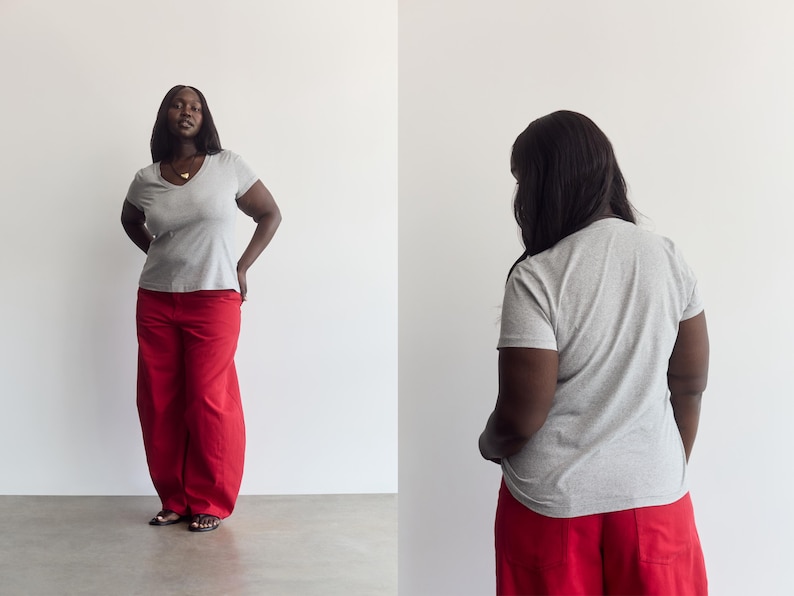 K&ouml;nnte beinhalten: Ein hellgraues kurz&auml;rmeliges T-Shirt mit V-Ausschnitt kombiniert mit einer locker sitzenden roten Hose. Das T-Shirt hat ein schlichtes, einfarbiges Design, w&auml;hrend die Hose weit geschnitten ist und bis zum Boden reicht, was ein l&auml;ssiges Outfit ergibt.