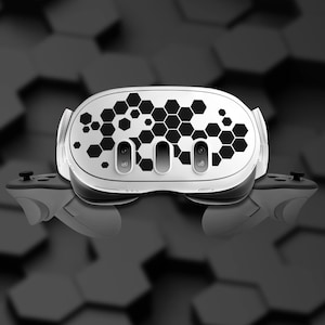 May include: A white virtual reality headset with a black honeycomb pattern design. The headset has two lenses and two sensors on the front.