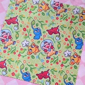 May include: A green fabric with a repeating pattern of cartoon characters in yellow, red, and blue, with floral and leaf accents. The background is a light green color. The fabric is set against a pink and white checkered background.