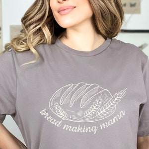 May include: A gray t-shirt with a white graphic of a loaf of bread and wheat stalks. The text "bread making mama" is written below the graphic.