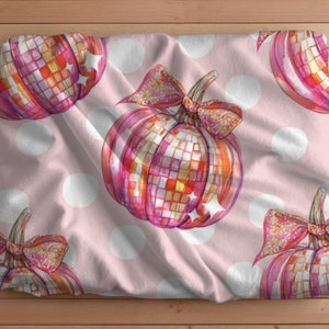 May include: Pink fabric with a white polka dot pattern featuring a repeating pattern of pink and orange glitter pumpkins with a disco ball effect.