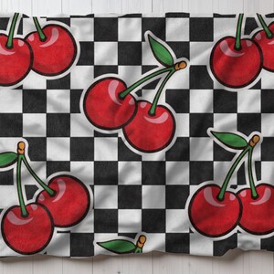 Puede incluir: Una tela a cuadros blancos y negros con un patrón repetido de cerezas rojas. Las cerezas están dibujadas en un estilo de dibujos animados con tallos y hojas verdes.
