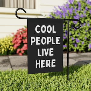May include: Black garden flag with white text that reads "Cool People Live Here".