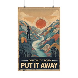 Könnte beinhalten: Ein vertikales Poster mit einer Landschaft aus Kleiderstapeln, einem Wäschekorb und einer Waschmaschinentür als Sonne. Eine Silhouette steht auf dem Korb. Der Text lautet: DON'T PUT IT DOWN, PUT IT AWAY. Die Farbpalette ist in gedeckten Tönen gehalten.