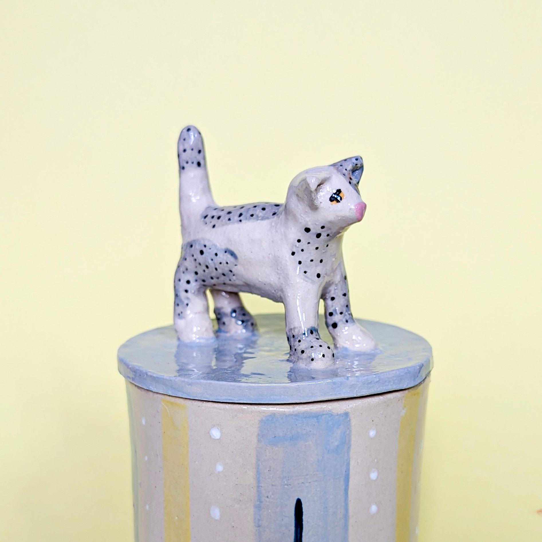 猫の形の陶器製置物 猫の形をした陶器の箱。水色、黄色、ベージュの猫の置物があしらわれた