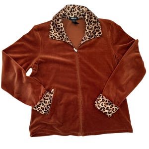 Puede incluir: Una chaqueta de terciopelo marrón con cremallera, cuello y puños de estampado de leopardo.