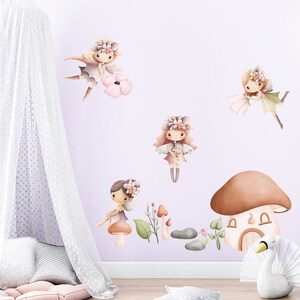 May include: A set of four fairy wall decals with floral crowns and wings. The fairies are in various poses and are surrounded by flowers and mushrooms. The decals are perfect for adding a touch of whimsy to a child's room.