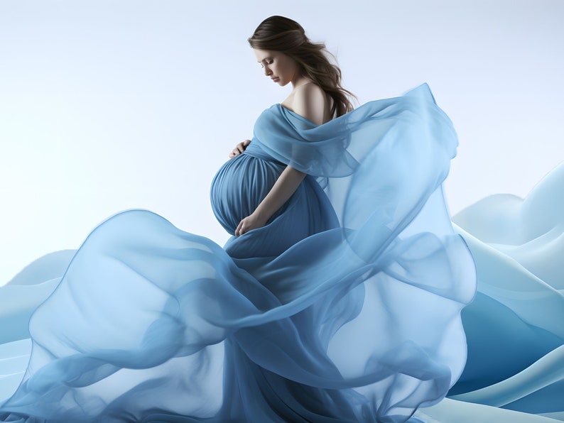 May include: A pregnant woman in a flowing light blue gown poses against a backdrop of blue and white waves. The gown is made of a sheer fabric that billows around her.