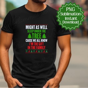 May include: A black t-shirt with a Christmas-themed design. The text on the shirt reads "Might as well sleep under the tree cause we all know I'm the gift in the family".